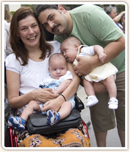 Cadeirante sorrindo com seu marido e filhos g�meos.